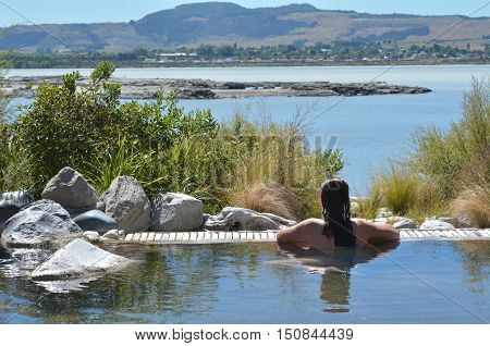 Young woman having a spa in outdoors hot pool in Rotorua New Zealand.