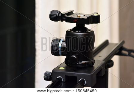 Tripod ball head mounted on linear camera slider.