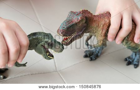 kids playing two tyrannosaurus toys on a sofa at home