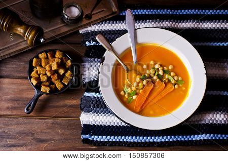 Pumpkin and carrot soup with chickpeas on a dark background. Selective focus.