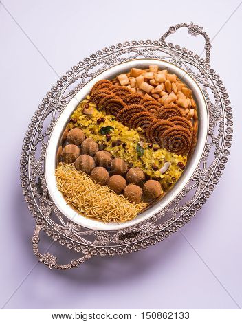 Plate full of indian festival food or diwali food or snacks like laddu, chivda, chakali or murukku, sev and shankar pale, sweet and salty snack food