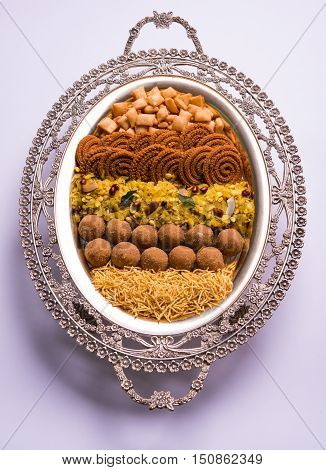 Plate full of indian festival food or diwali food or snacks like laddu, chivda, chakali or murukku, sev and shankar pale, sweet and salty snack food