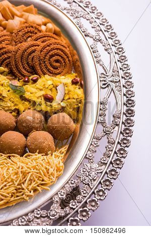 Plate full of indian festival food or diwali food or snacks like laddu, chivda, chakali or murukku, sev and shankar pale, sweet and salty snack food