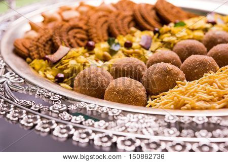 Plate full of indian festival food or diwali food or snacks like laddu, chivda, chakali or murukku, sev and shankar pale, sweet and salty snack food