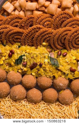 Plate full of indian festival food or diwali food or snacks like laddu, chivda, chakali or murukku, sev and shankar pale, sweet and salty snack food