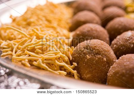 Plate full of indian festival food or diwali food or snacks like laddu, chivda, chakali or murukku, sev and shankar pale, sweet and salty snack food