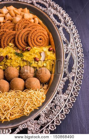 Plate full of indian festival food or diwali food or snacks like laddu, chivda, chakali or murukku, sev and shankar pale, sweet and salty snack food