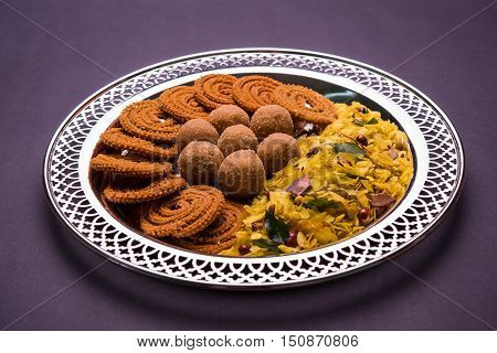 Plate full of indian festival food or diwali food or snacks like laddu, chivda, chakali or murukku, sev and shankar pale, sweet and salty snack food