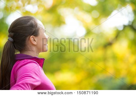 Profile portrait of an attractive smiling woman outdoors in sportswear, looking forward to the tellow forest. Concept photo, side view, copyspace