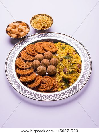Plate full of indian festival food or diwali food or snacks like laddu, chivda, chakali or murukku, sev and shankar pale, sweet and salty snack food