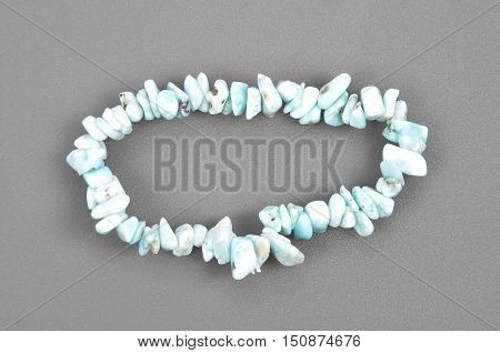 Colorful and crisp image of splintered larimar chain on gray background