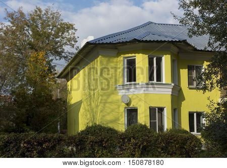 The yellow building with two floors and rectangular Windows Dating from the mid 20th century standing among autumn trees under a blue sky Russia Novomoskovsk