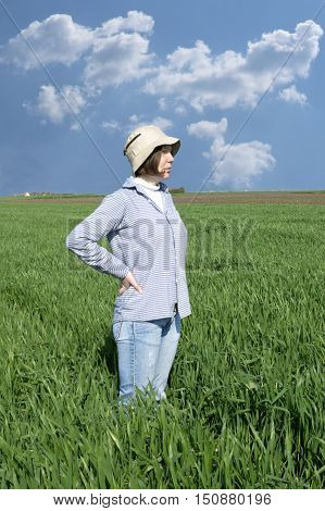 Female farmer in a weath field against blue sky.