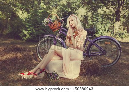 Girl hugging a toy bear in the park next to her bike.