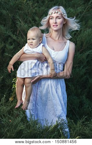 Young mother holding a child they are dressed in a white robe.