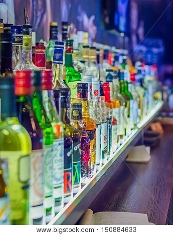Many bottles of different alcohol by barrels