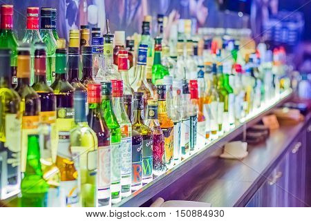Many bottles of different alcohol by barrels