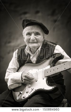 Elderly woman playing a guitar. Selective focus.