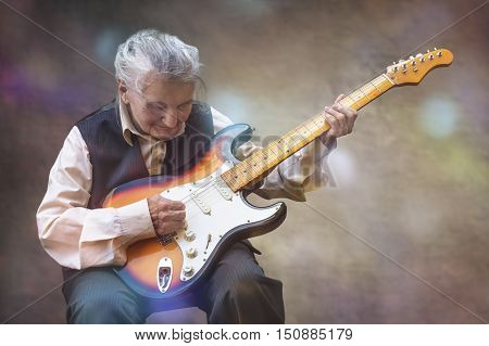 Elderly woman playing a guitar. Selective focus.