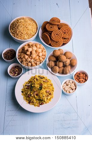 homemade tasty Diwali food or Diwali snacks or Diwali sweets like rava laddu, chakli, sev, shankar pale and chivda or chiwada with dry fruits in white bowls, favourite indian diwali recipe