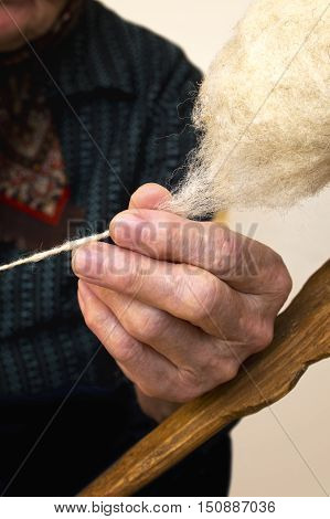 Old hand spinning wool. Selective focus on hand.