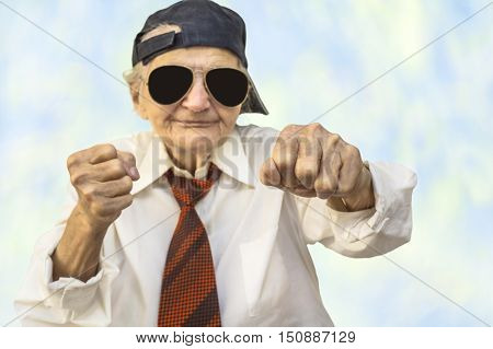 Funny elderly woman wearing cap in a fight pose. Selective focus.
