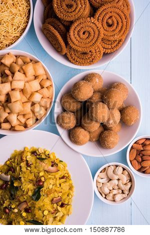 homemade tasty Diwali food or Diwali snacks or Diwali sweets like rava laddu, chakli, sev, shankar pale and chivda or chiwada with dry fruits in white bowls, favourite indian diwali recipe