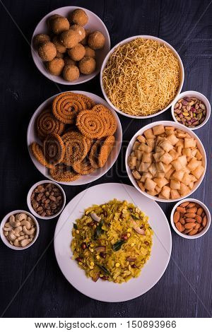 homemade tasty Diwali food or Diwali snacks or Diwali sweets like rava laddu, chakli, sev, shankar pale and chivda or chiwada with dry fruits in white bowls, favourite indian diwali recipe