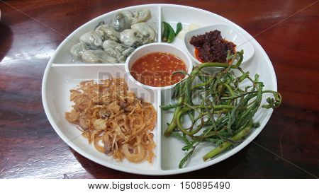 Oysters with herbs in white plate on table