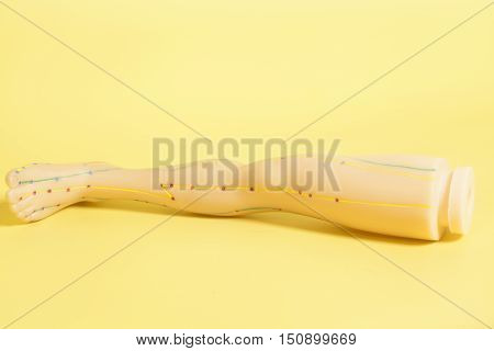 Medical acupuncture model of human feet on yellow background