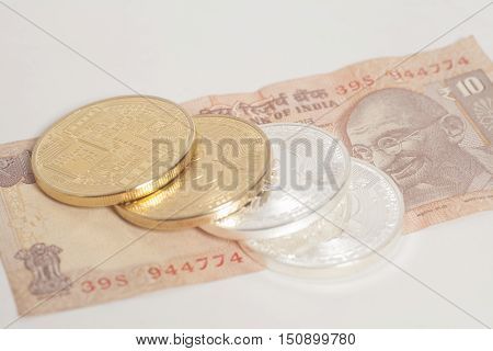 Golden and silver bitcoin coins on Indian Ten Rupee on white background
