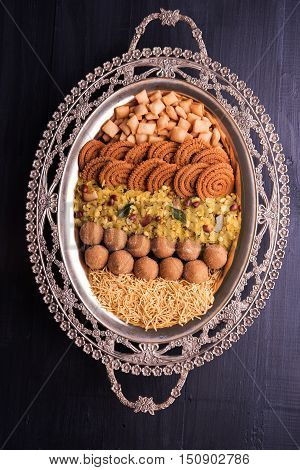 Plate full of indian festival food or diwali food or snacks like laddu, chivda, chakali or murukku, sev and shankar pale, sweet and salty snack food