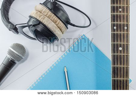 neck guitar notebook in top view with music concept whitebackground headphones