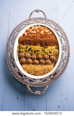 Plate full of indian festival food or diwali food or snacks like laddu, chivda, chakali or murukku, sev and shankar pale, sweet and salty snack food