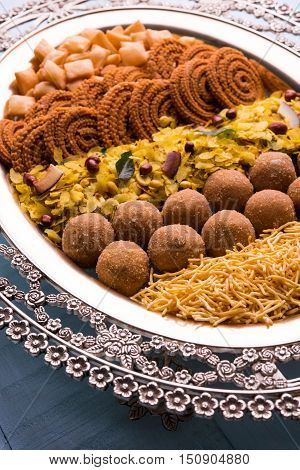 Plate full of indian festival food or diwali food or snacks like laddu, chivda, chakali or murukku, sev and shankar pale, sweet and salty snack food