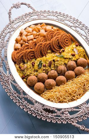 Plate full of indian festival food or diwali food or snacks like laddu, chivda, chakali or murukku, sev and shankar pale, sweet and salty snack food