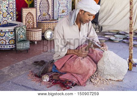 Badajoz Spain - September 24 2016: Artisan makes pieces for mosaic craftwork. He is shaping pieces from glazed tiles