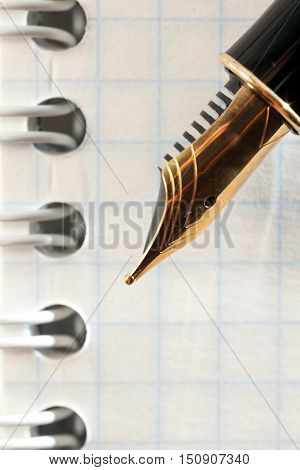 Gold fountain pen close-up on notebook sheet. Photo closeup Pen