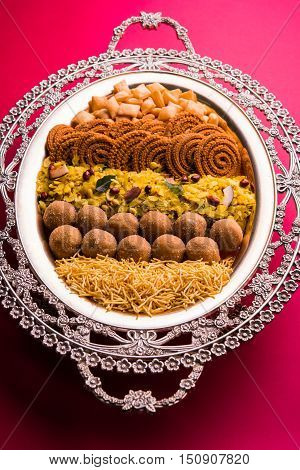 Plate full of indian festival food or diwali food or snacks like laddu, chivda, chakali or murukku, sev and shankar pale, sweet and salty snack food