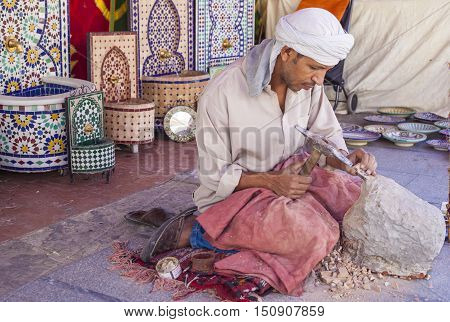 Badajoz Spain - September 24 2016: Artisan makes pieces for mosaic craftwork. He is shaping pieces from glazed tiles