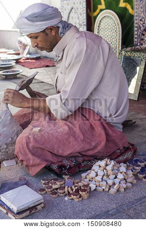 Badajoz Spain - September 24 2016: Artisan makes pieces for mosaic craftwork. He is shaping pieces from glazed tiles