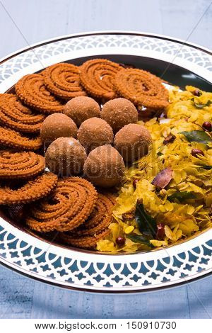 Plate full of indian festival food or diwali food or snacks like laddu, chivda, chakali or murukku, sev and shankar pale, sweet and salty snack food