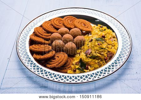 Plate full of indian festival food or diwali food or snacks like laddu, chivda, chakali or murukku, sev and shankar pale, sweet and salty snack food