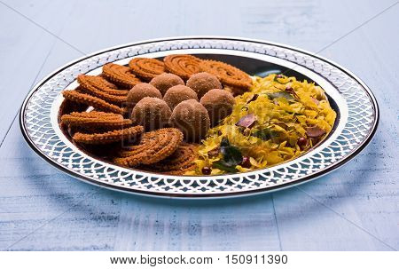 Plate full of indian festival food or diwali food or snacks like laddu, chivda, chakali or murukku, sev and shankar pale, sweet and salty snack food
