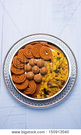 Plate full of indian festival food or diwali food or snacks like laddu, chivda, chakali or murukku, sev and shankar pale, sweet and salty snack food
