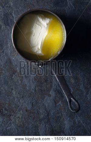 Melted butter in the stewpan on the stone background vertical