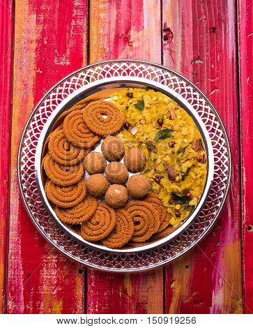 Plate full of indian festival food or diwali food or snacks like laddu, chivda, chakali or murukku, sev and shankar pale, sweet and salty snack food