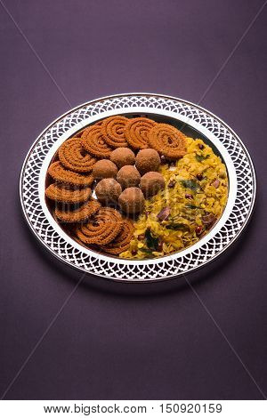Plate full of indian festival food or diwali food or snacks like laddu, chivda, chakali or murukku, sev and shankar pale, sweet and salty snack food