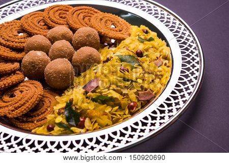 Plate full of indian festival food or diwali food or snacks like laddu, chivda, chakali or murukku, sev and shankar pale, sweet and salty snack food