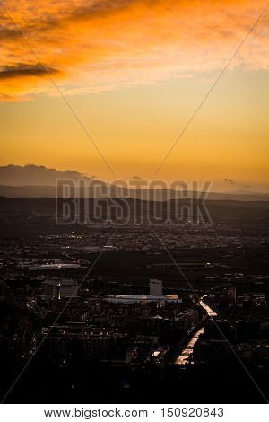 Panoramic view of the city of Granada, Genil river and the Vega of Granada at sunset under a cloudy sky making up some reflections